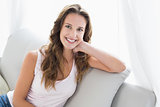 Smiling young woman sitting on sofa in living room
