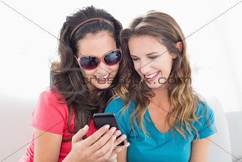 Female friends in sunglasses reading text message