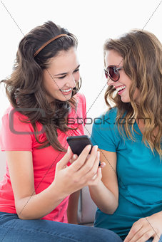 Female friends in sunglasses reading text message
