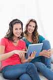 Female friends using digital tablet in the living room