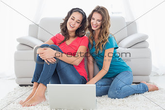 Female friends using laptop in the living room