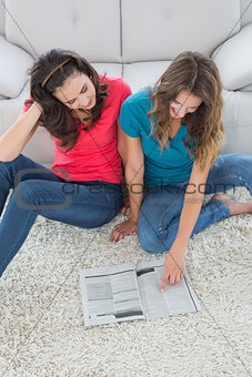 Female friends reading a book in the living room