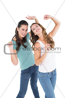 Two cheerful young female friends dancing
