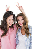 Female friends gesturing peace sign over heads