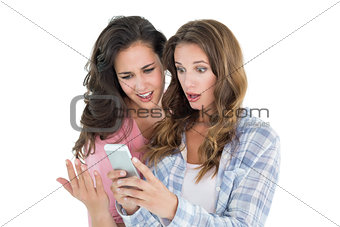 Shocked female friends looking at mobile phone