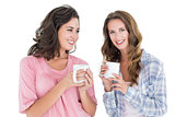 Two smiling young female friends drinking coffee