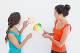 Two female friends choosing color for painting a room