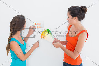 Two female friends choosing color for painting a room