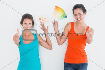 Female friends with color swatches gesturing thumbs up