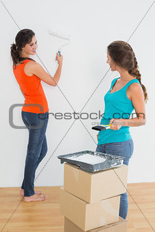 Female friends with paint brushes in a new house
