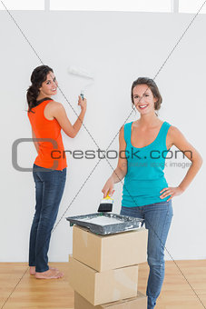 Female friends with paint brushes in a new house