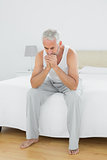 Thoughtful mature man sitting in bed