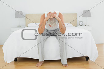 Thoughtful mature man sitting in bed