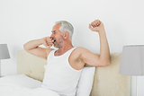 Mature man stretching his arms at home