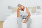 Thoughtful mature man yawning in bed