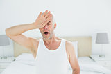 Mature man yawning in bed