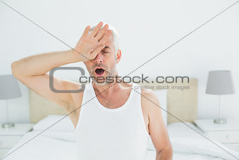 Mature man yawning in bed