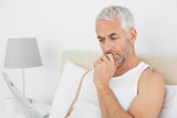 Mature man reading newspaper in bed