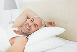 Close-up of a smiling mature man resting in bed