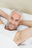 Portrait of a smiling mature man resting in bed