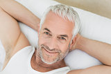 Close-up of a smiling mature man resting in bed