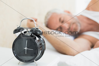 Man sleeping in bed with alarm clock in foreground