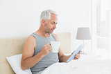 Mature man with digital tablet and coffee table in bed