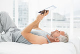 Relaxed mature man using digital tablet in bed