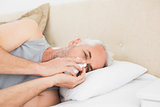 Close-up of a mature man suffering from cold in bed