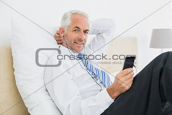 Businessman listening music with his phone in bed