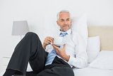 Relaxed businessman with a cup of tea in bed