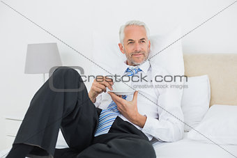 Relaxed businessman with a cup of tea in bed