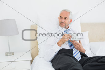 Well dressed mature man with a cup of tea in bed