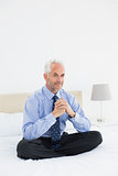 Relaxed smiling mature businessman sitting in bed