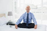 Relaxed businessman sitting with eyes closed on bed