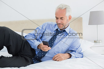 Relaxed well dressed man text messaging in bed