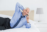 Mature businessman using mobile phone in bed