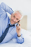 Mature businessman using mobile phone in bed