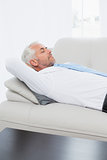 Tired mature businessman sleeping on sofa in living room