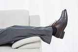 Low section side view of a businessman resting on sofa