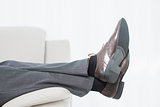 Low section side view of a businessman resting on sofa