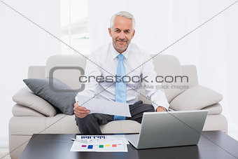Businessman working on graphs and laptop at home