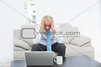 Portrait of a worried mature businessman with laptop at home
