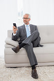Elegant mature businessman text messaging at home