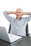 Businessman sitting with hands behind head with laptop