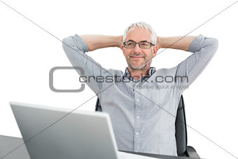 Businessman sitting with hands behind head and laptop