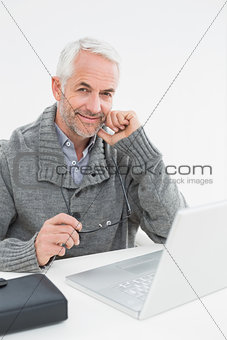 Portrait of a smiling mature man with laptop at desk