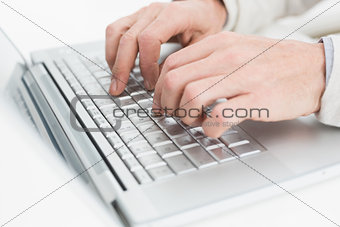 Hands using laptop on white surface