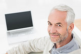 Close-up portrait of a grey haired man with laptop
