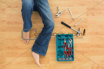 Man lying with several tools on parquet floor
